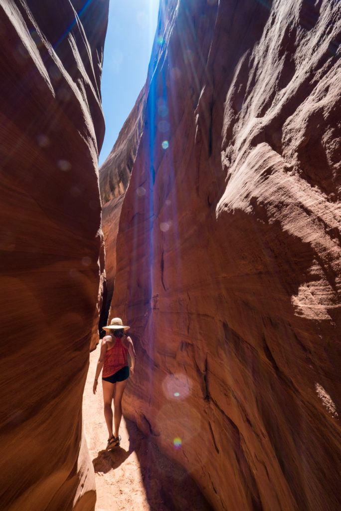 Kristen walking through narrow red rock Labyrinth Canyon in Arizona