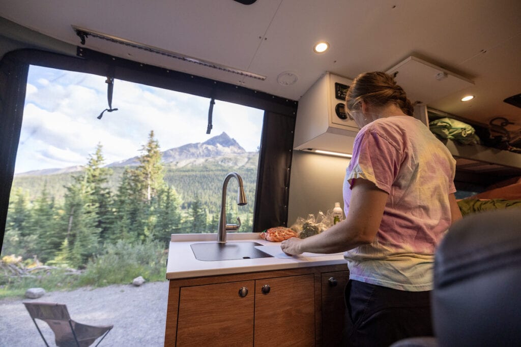 Kristen Bor cooking in Sprinter Van with bug screen over the door