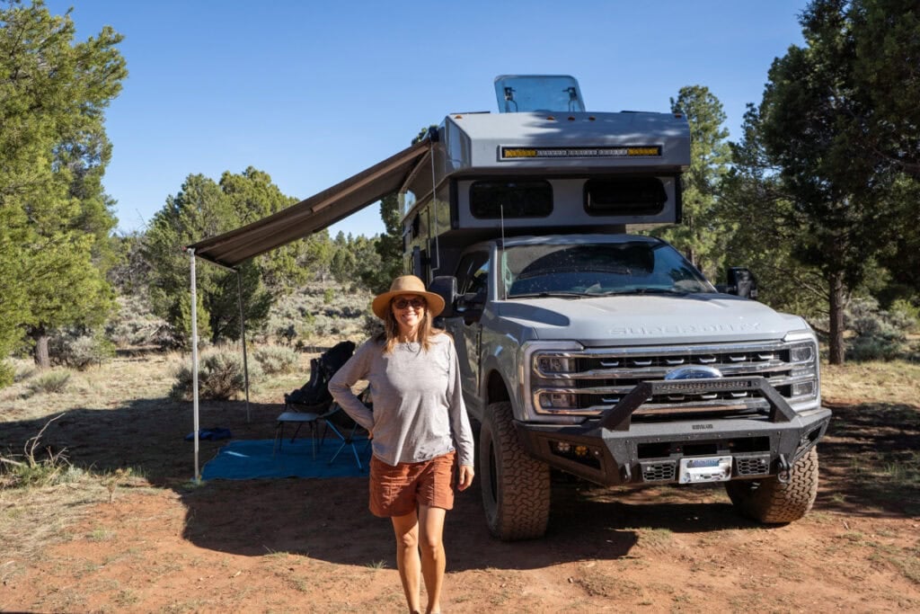Kristen Bor standing next to a Rossmonster Baja Trail adventure truck camper at a desert campsite