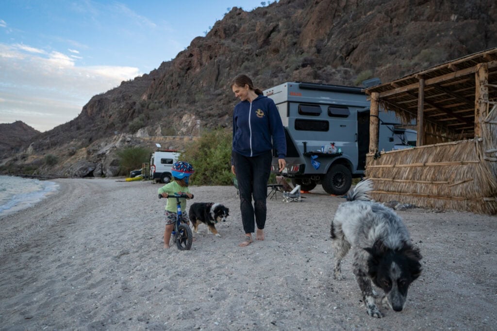 Kristen Bor and her son on a strider bike standing next to Rossmonster Baja Trail on a beach in Baja