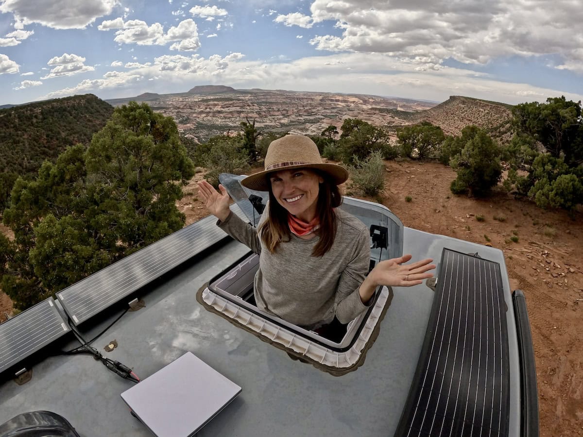 Kristen Bor popping through the skylight on the roof of the Rossmonster Baja Trail adventure truck at a free desert campsite with an incredible view