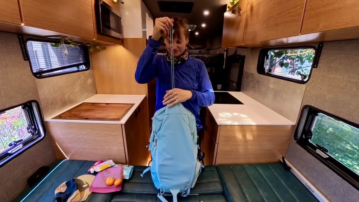 Kristen Bor packing a deuter trail backpack in a rossmonster truck camper