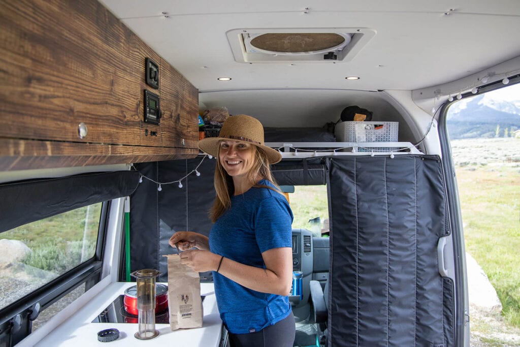 A woman using the Aeropress Go Travel Coffee Press in her Sprinter van