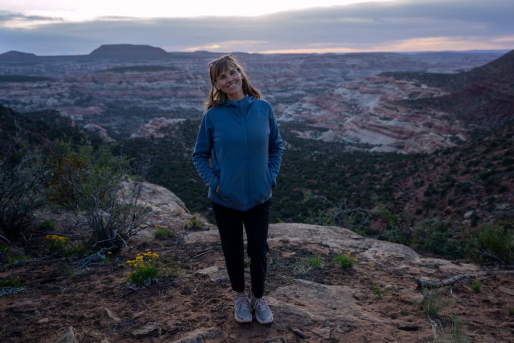 Kristen Bor standing on the edge of a desert canyon at sunset