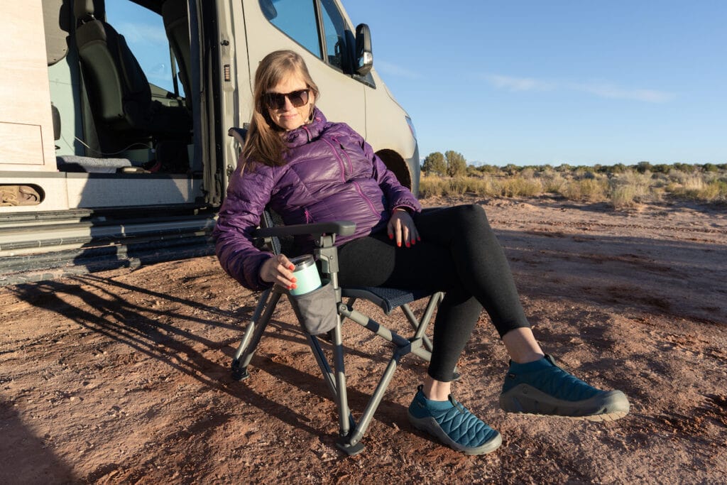 Kristen relaxing in Yeti Camp chair at desert campsite with Sprinter van behind her