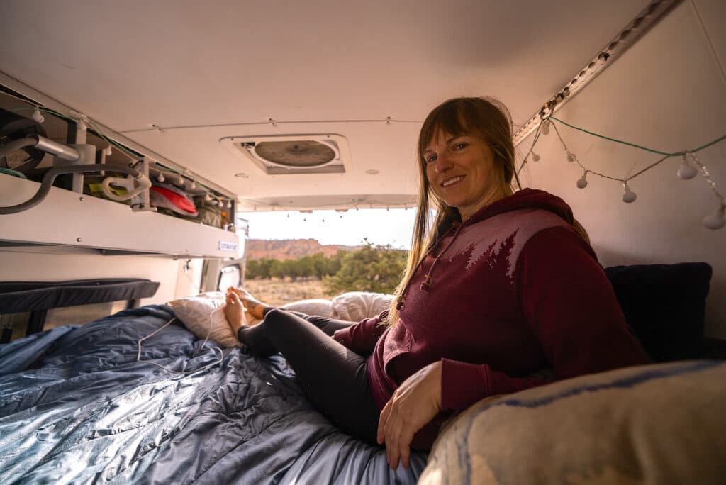 Bearfoot Theory founder Kristen Bor in the bed in the back of her Sprinter camper van parked near Bryce Canyon National Park