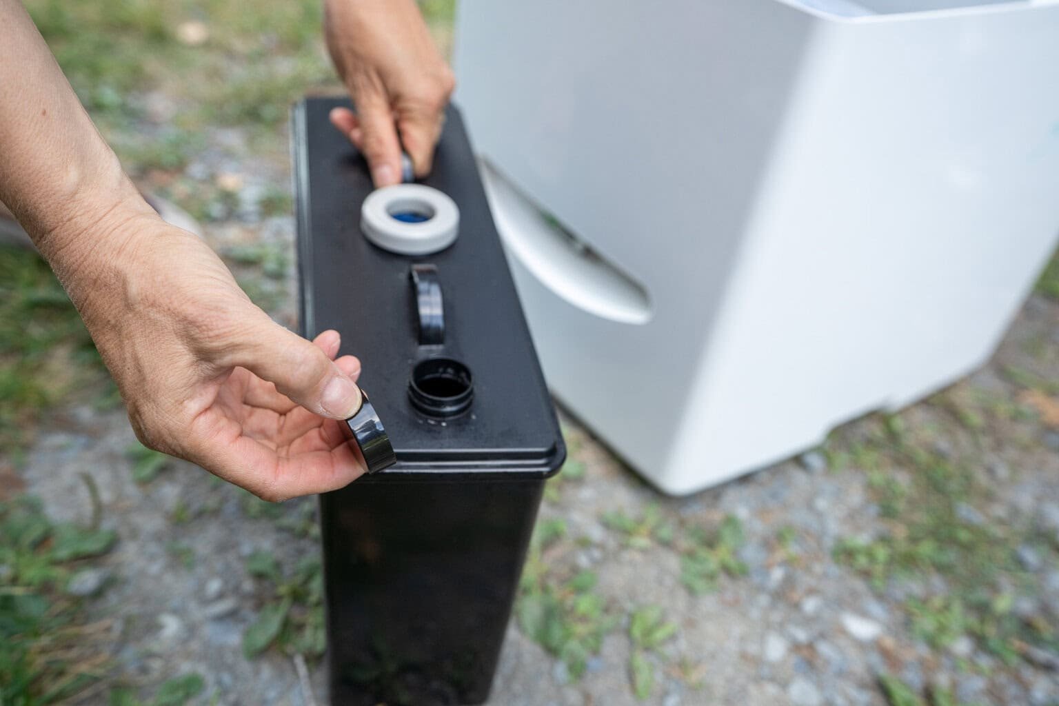 Kristen Bor demonstrating how to use the Compocloset Cuddy Lite composting toilet standing in front of a truck camper