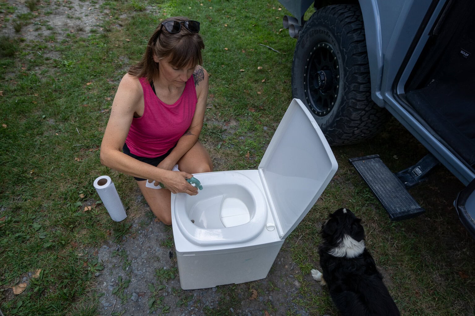 Kristen Bor demonstrating how to use the Compocloset Cuddy Lite composting toilet standing in front of a truck camper
